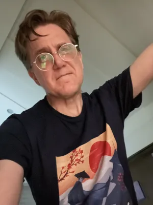 John wearing a "Blue Eye Samurai" tee and looking gravely at the camera